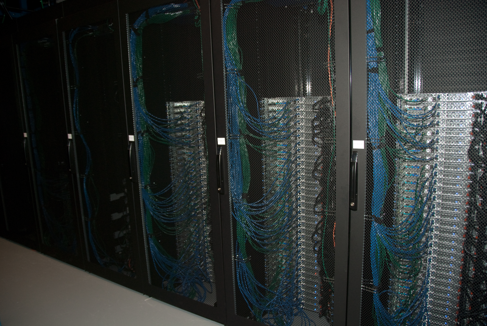 [Stacks of server computers connected by green and blue ethernet cables.]